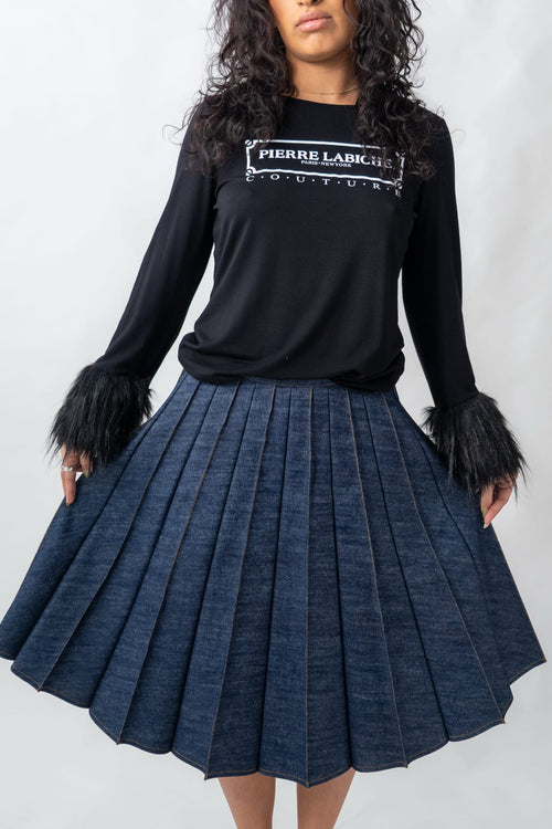 Female wearing a large sunburst pleated denim skirt with black long sleeve t-shirt