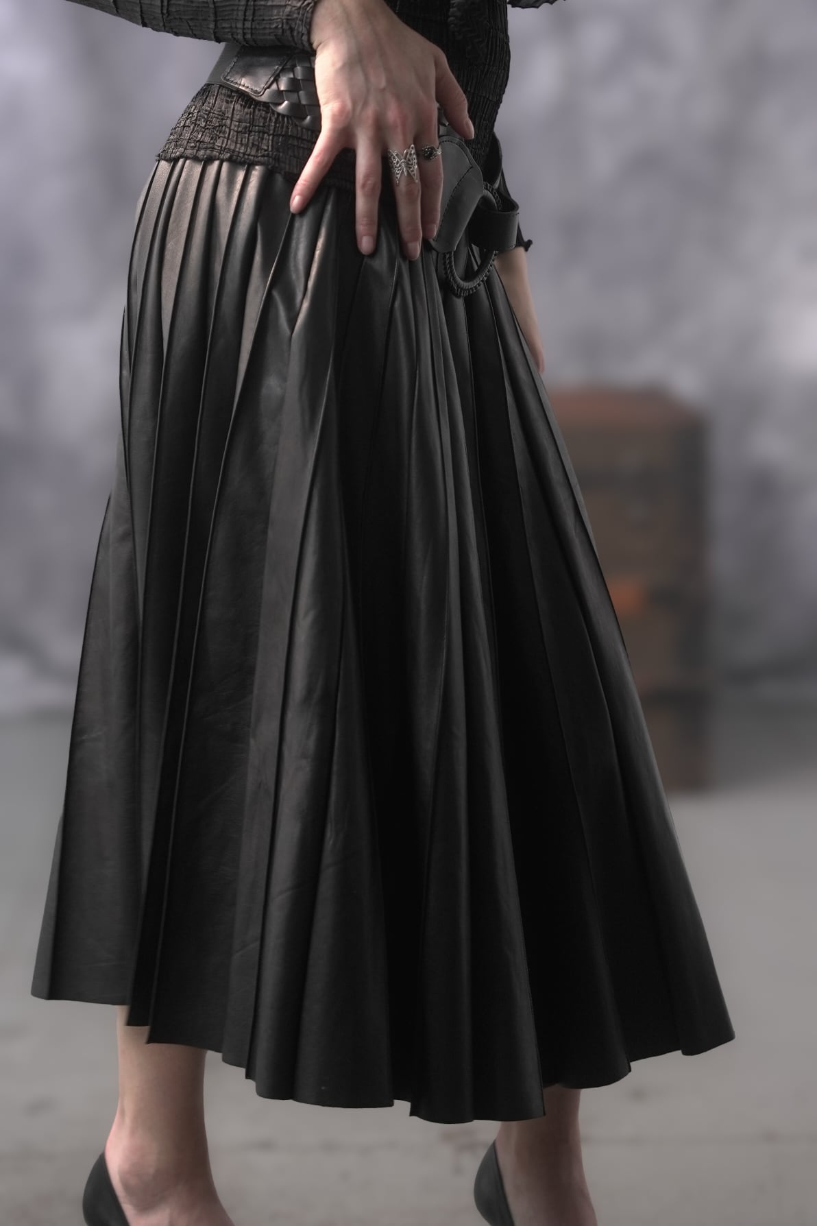 Person wearing a black pleated skirt with a blurred background