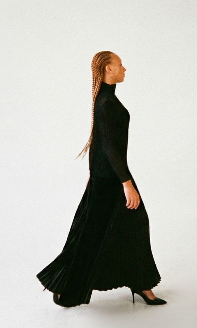 Woman wearing a long black pleated palazzo pant  on a white background